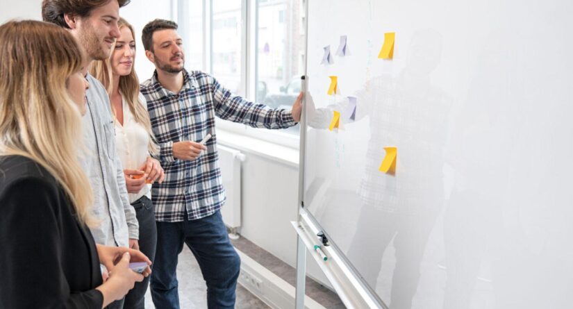 Mehrere Personen stehen vor einem White Board