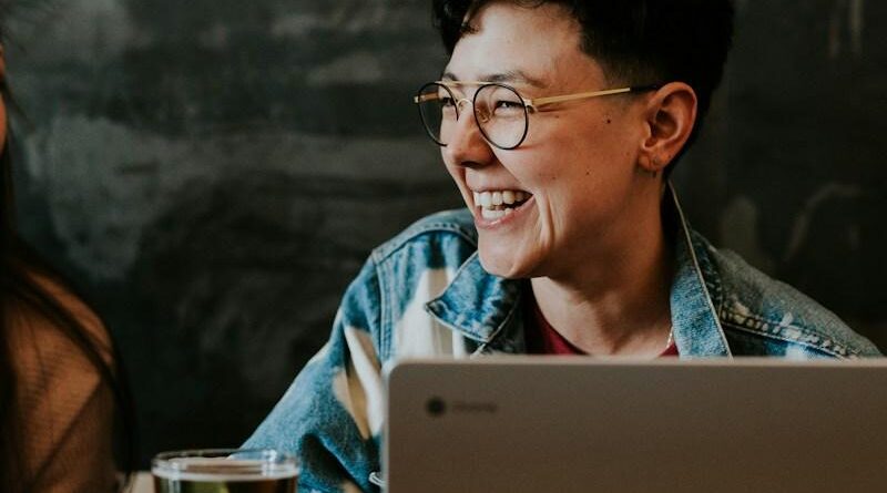 Lachende Frau vor Laptop sitzend